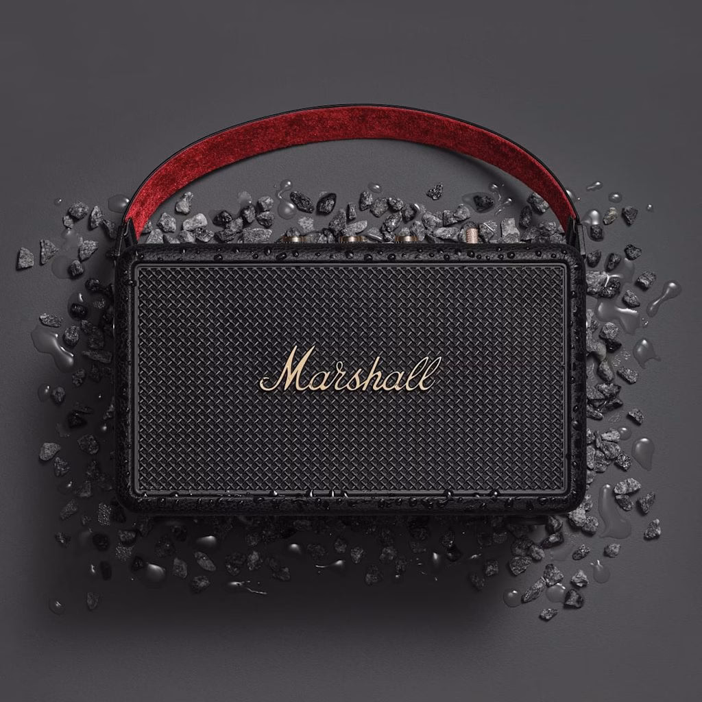Акустика Marshall Kilburn 3 Black and Brass стоїть на камінні в краплях води