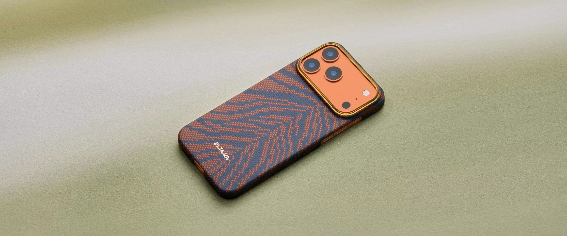 Кевларовий чохол Pitaka Breath of Veins Burning Orange для iPhone 17 Pro лежить на зеленому фоні.