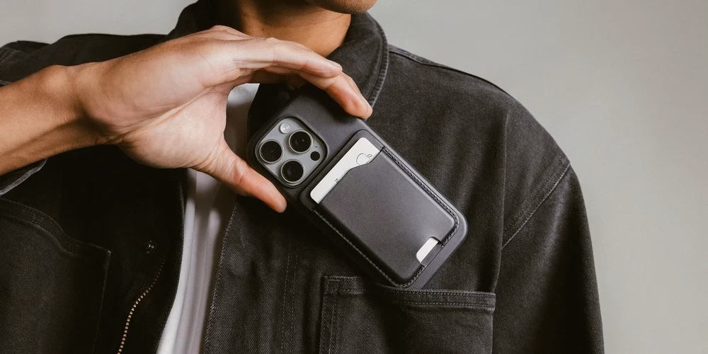 Чоловік дістає iPhone з гаманцем Nomad Leather Mag Wallet з кишені